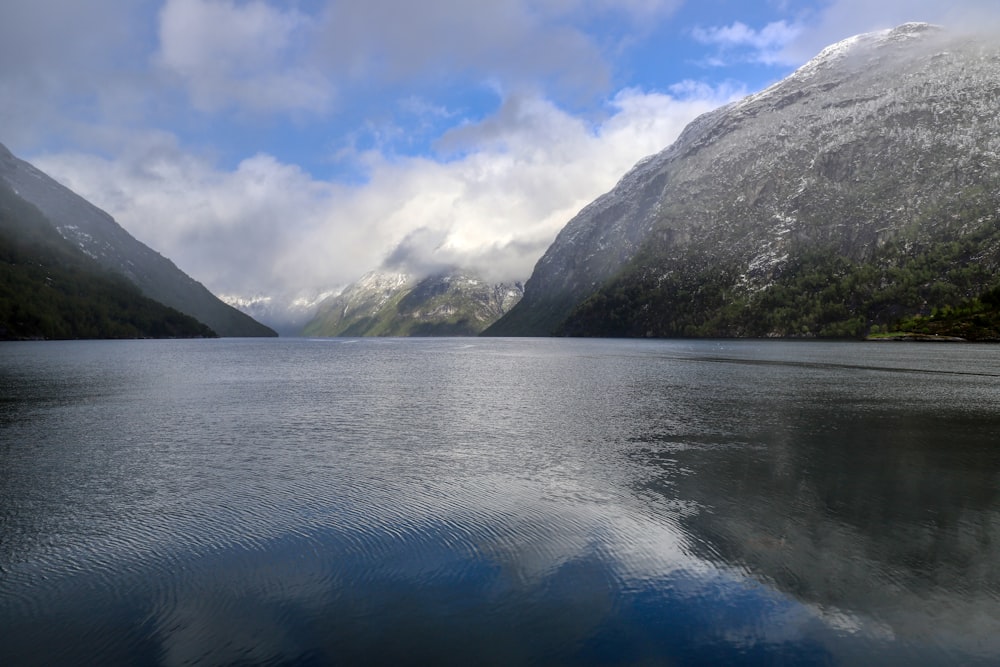 body of water near mountain under blue sky during daytime