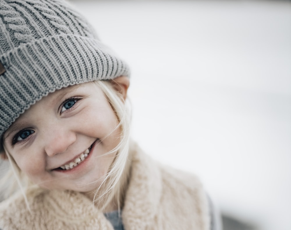 menina sorridente no boné de malha cinza