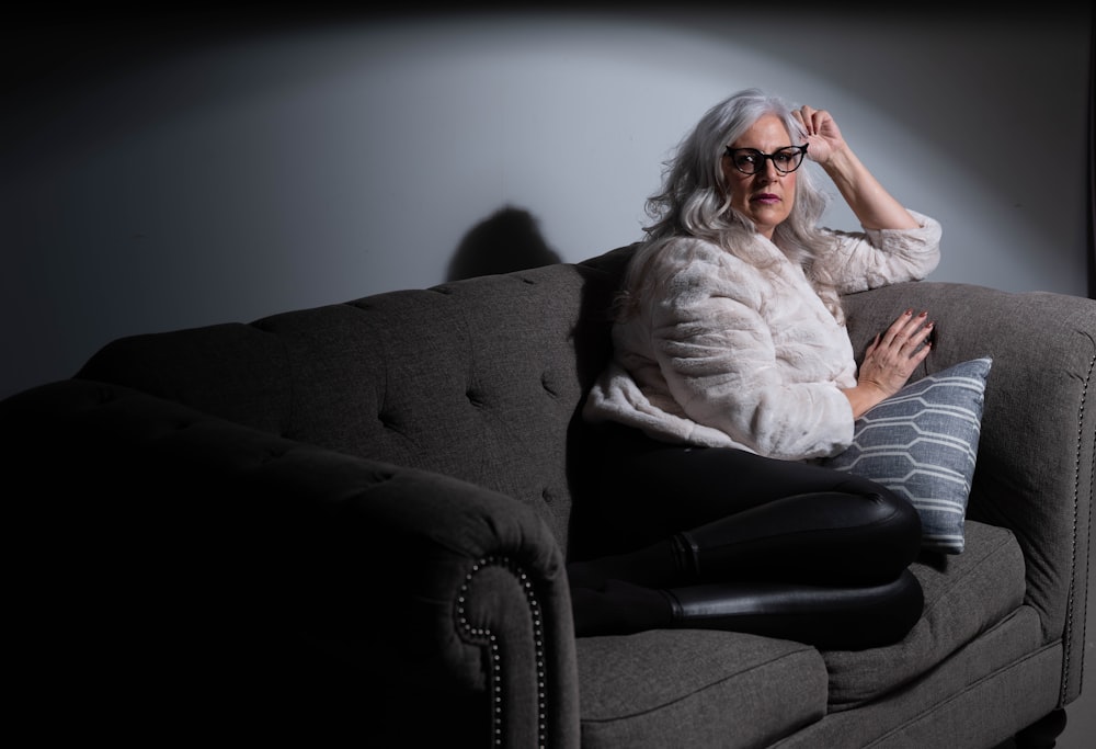 woman in white long sleeve shirt and black pants sitting on black sofa