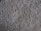 A close-up view of a textured, plush carpet with dense, fibrous strands in a neutral beige color.