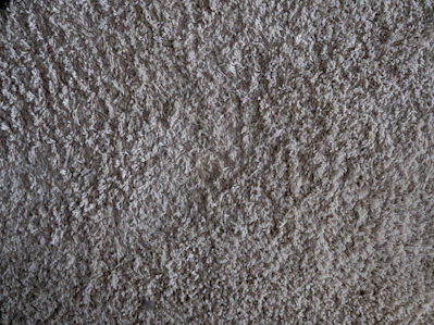 Close-up of a soft, anti-slip bathroom mat in neutral tones on a tiled bathroom floor