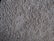 A close-up view of a textured, plush carpet with dense, fibrous strands in a neutral beige color.