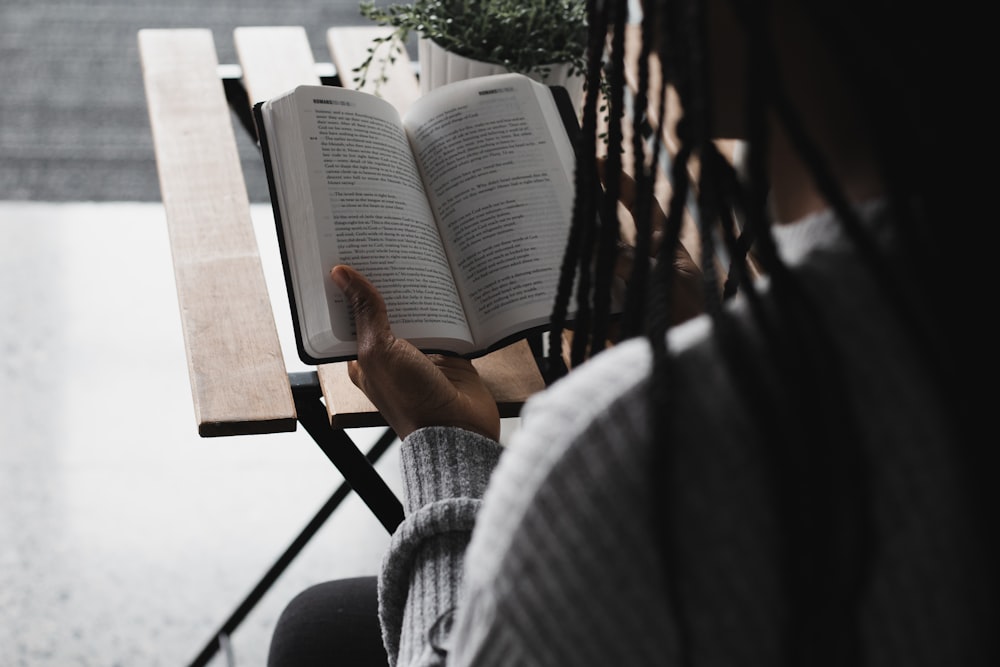 person in gray sweater holding white book