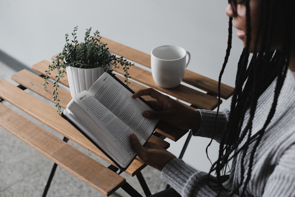 person reading book on brown wooden table