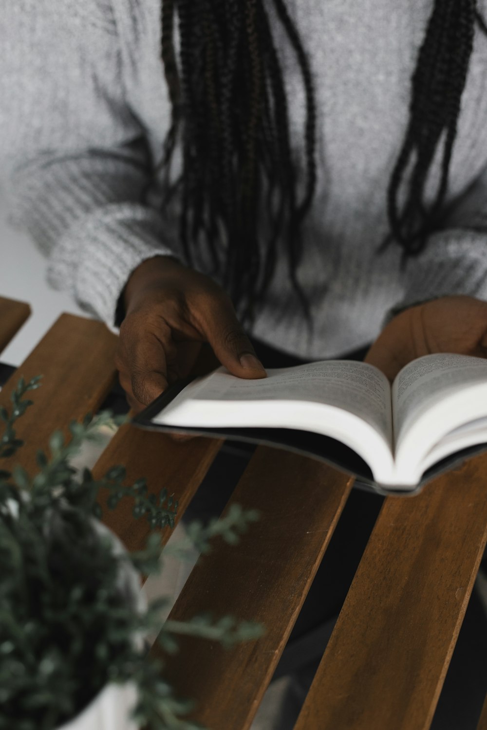 person reading book on brown wooden table