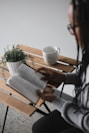 person holding white ceramic mug on brown wooden table