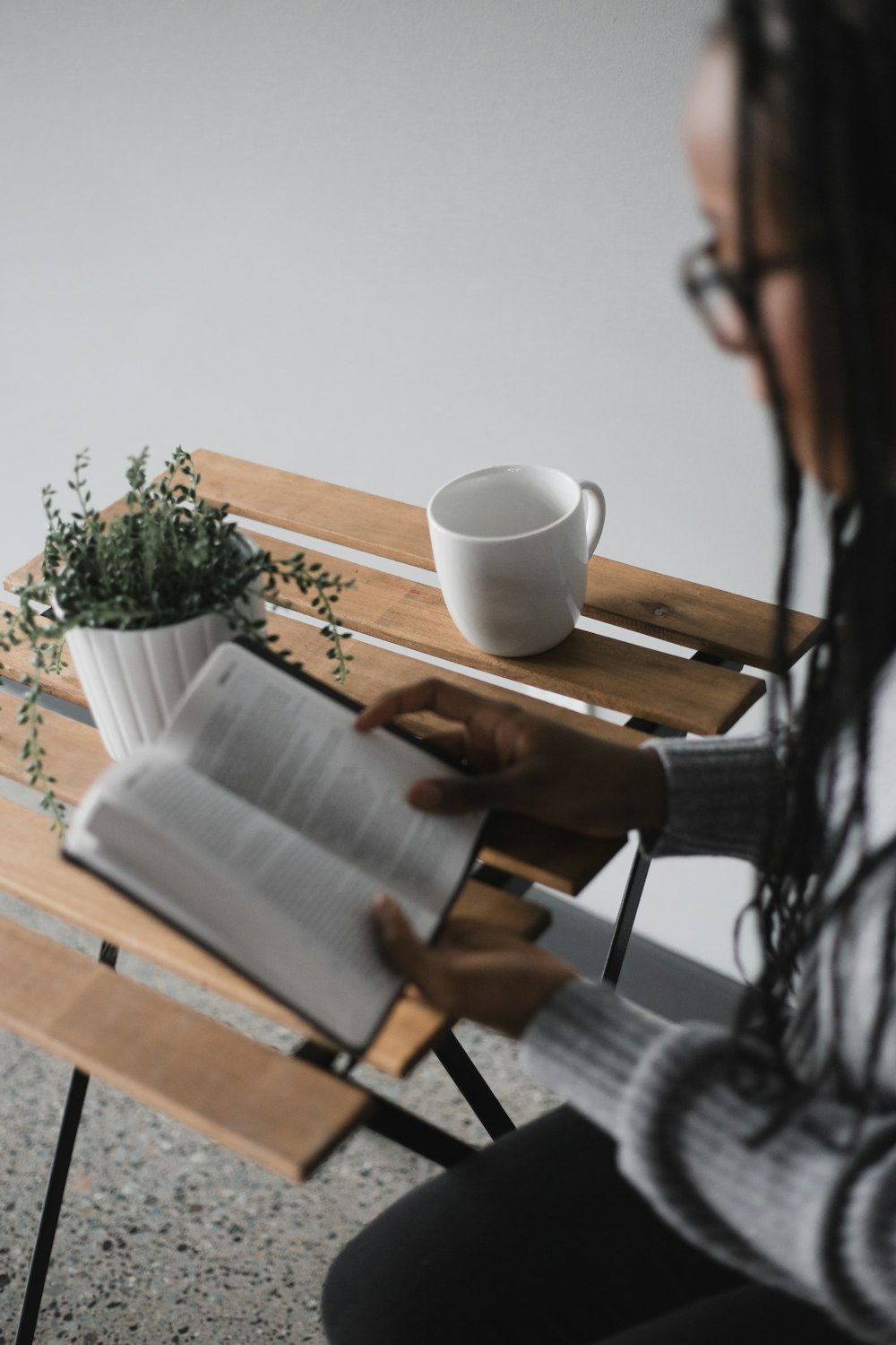 person holding white ceramic mug on brown wooden table