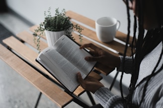 person writing on white book on brown wooden table