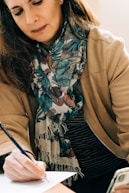 woman in brown coat with black white and red scarf