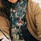 woman in brown coat with black white and red scarf