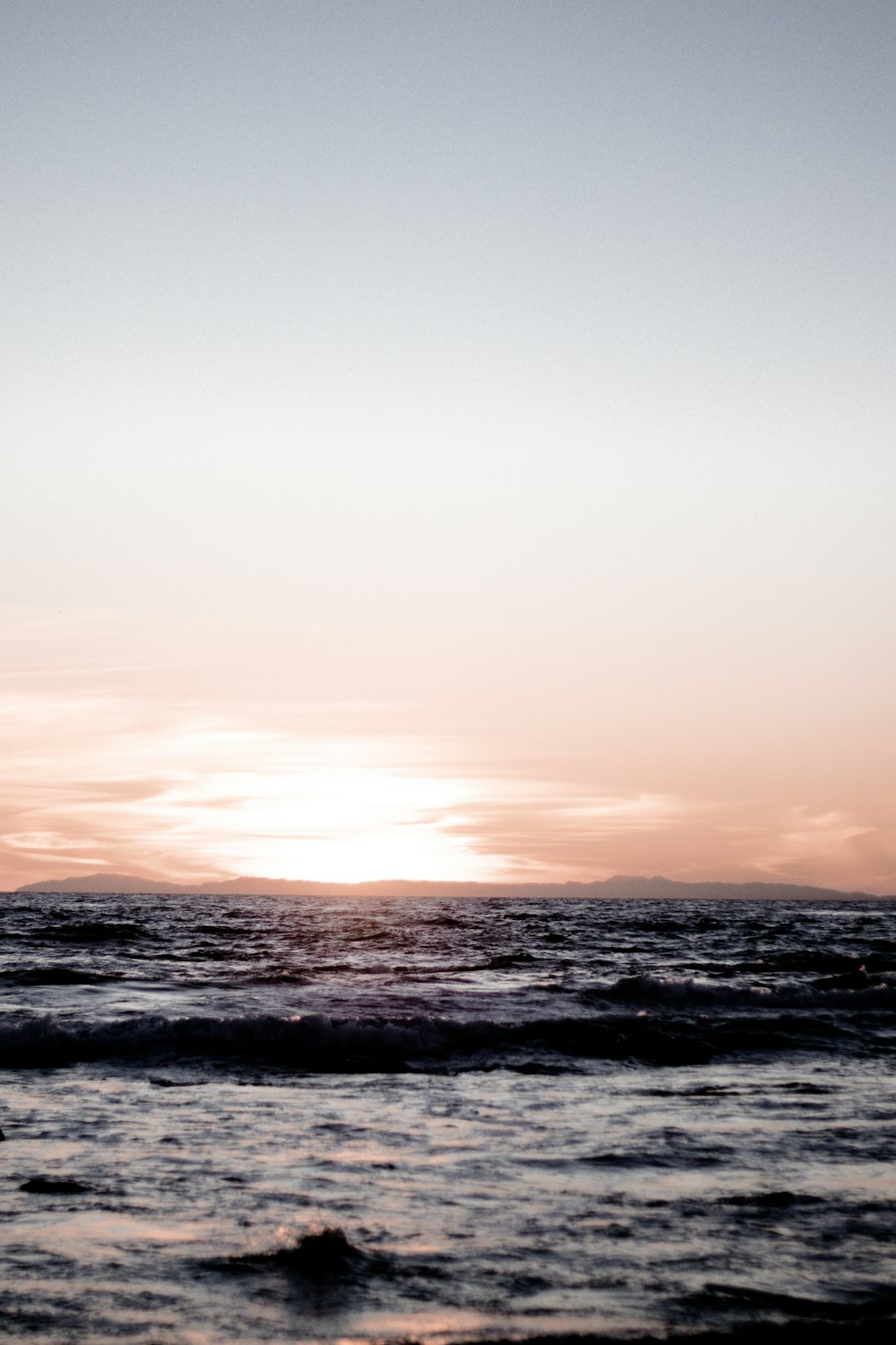 ocean waves crashing on shore during sunset