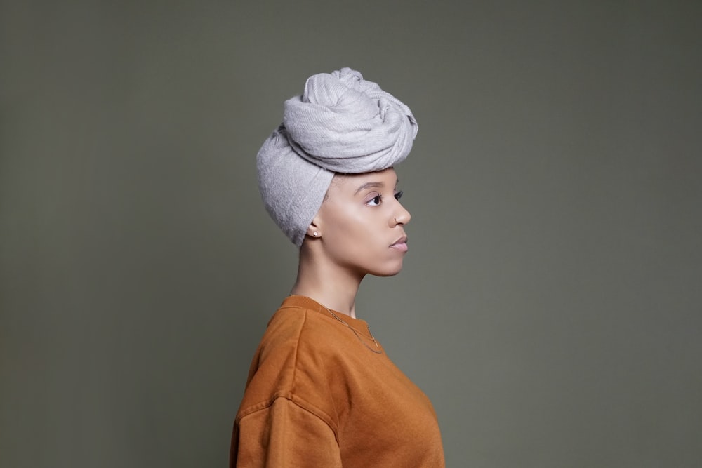 woman in orange shirt wearing white knit cap