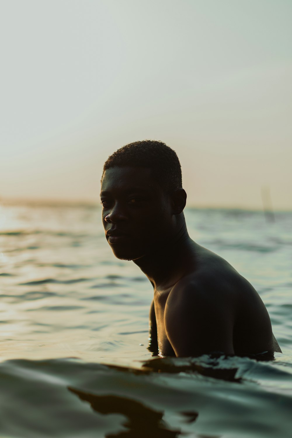 topless man sitting on shore during daytime