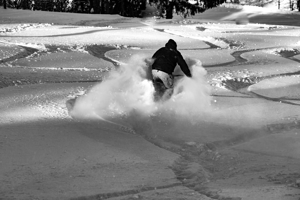 Persona con chaqueta negra montando en tabla de nieve blanca durante el día