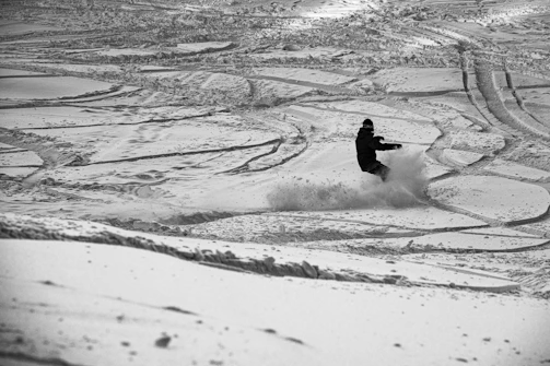 person riding on snowboard on snow covered ground during daytime