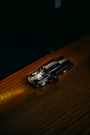 Shiny die-cast car model displayed on a wooden shelf with soft lighting.
