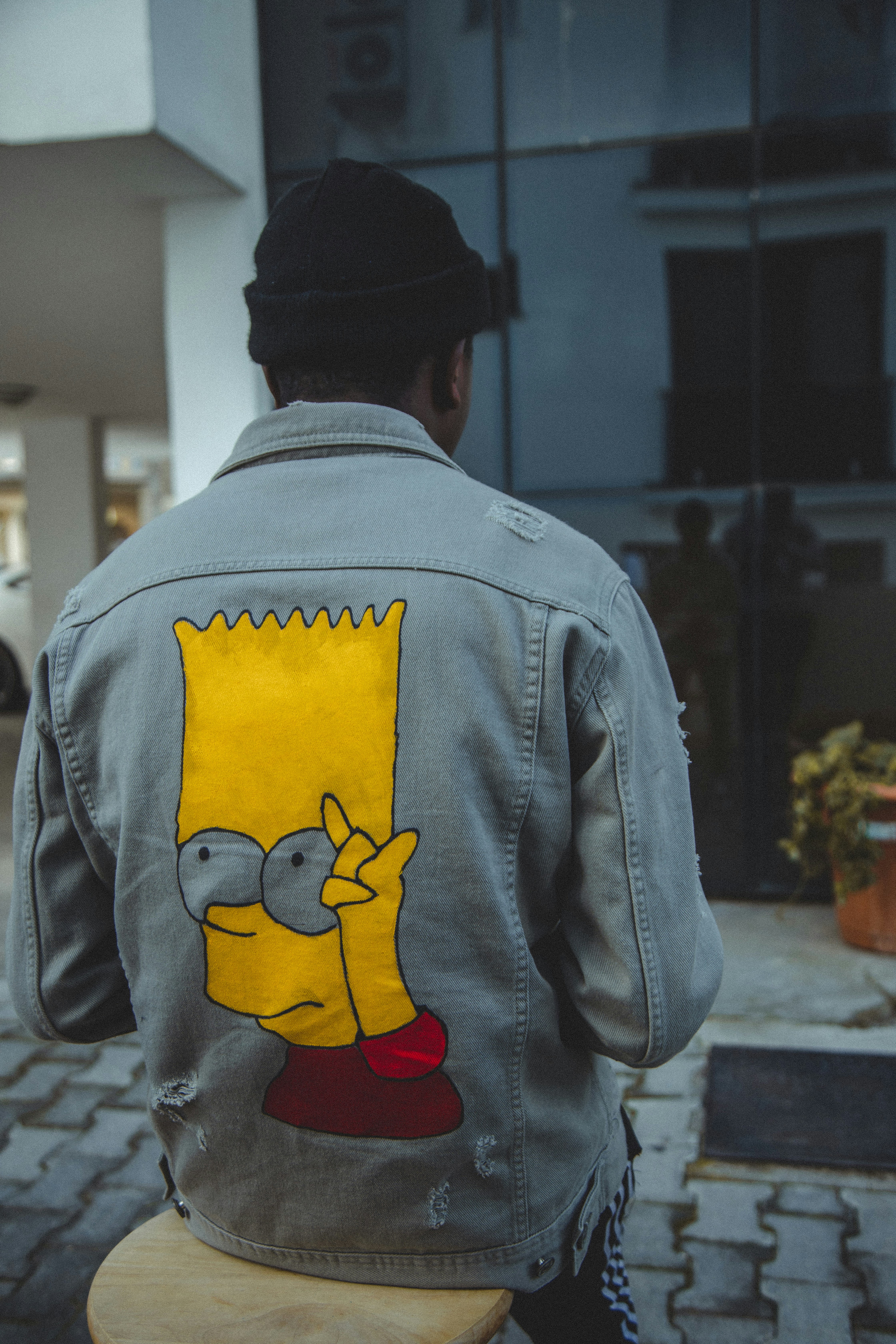 Hombre con chaqueta gris con gorra negra y amarilla de Batman