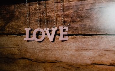 Wooden letters forming the word 'LOVE' hang from strings against a rustic wooden background.