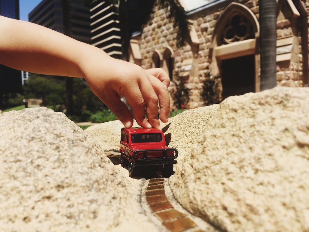 person holding red and black toy car