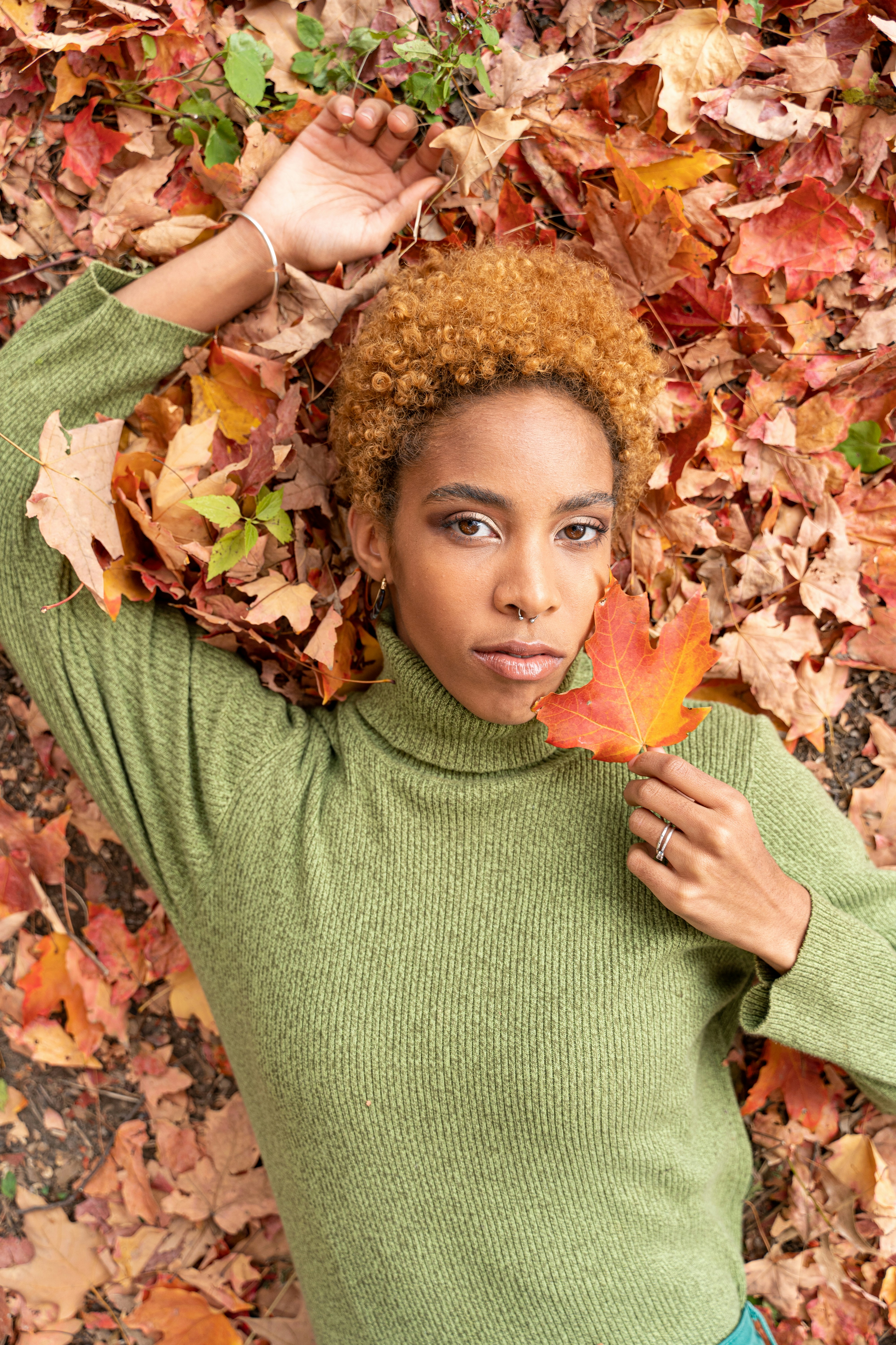 girl in green turtleneck sweater holding yellow maple leaf
