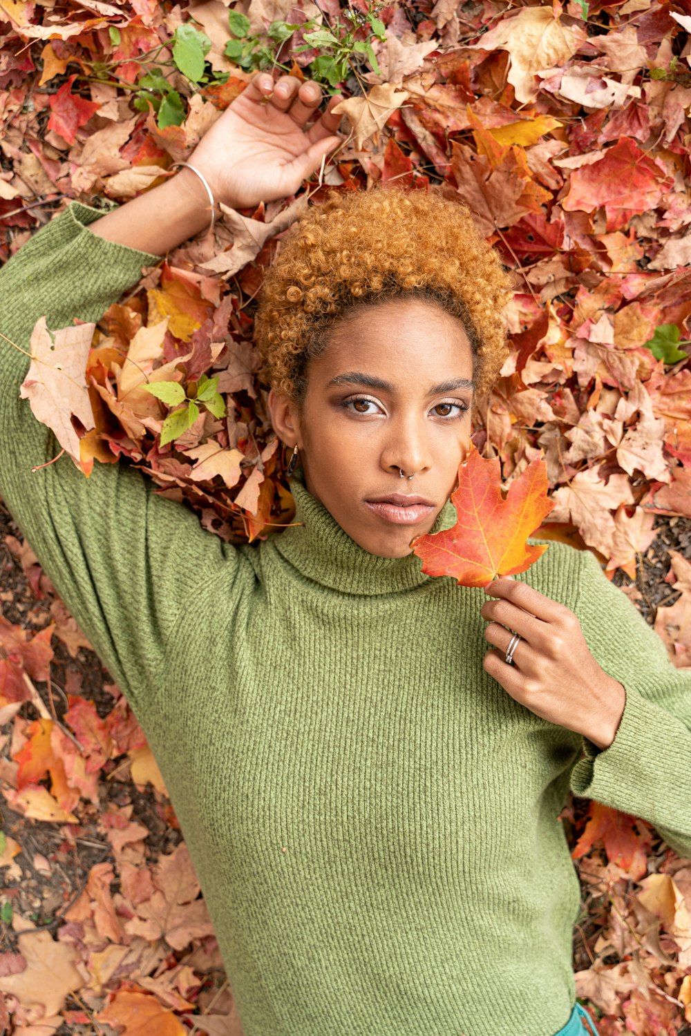 girl in green turtleneck sweater holding yellow maple leaf