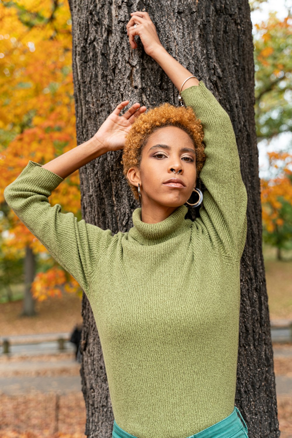 昼間、木のそばに立つ緑のセーターの女の子