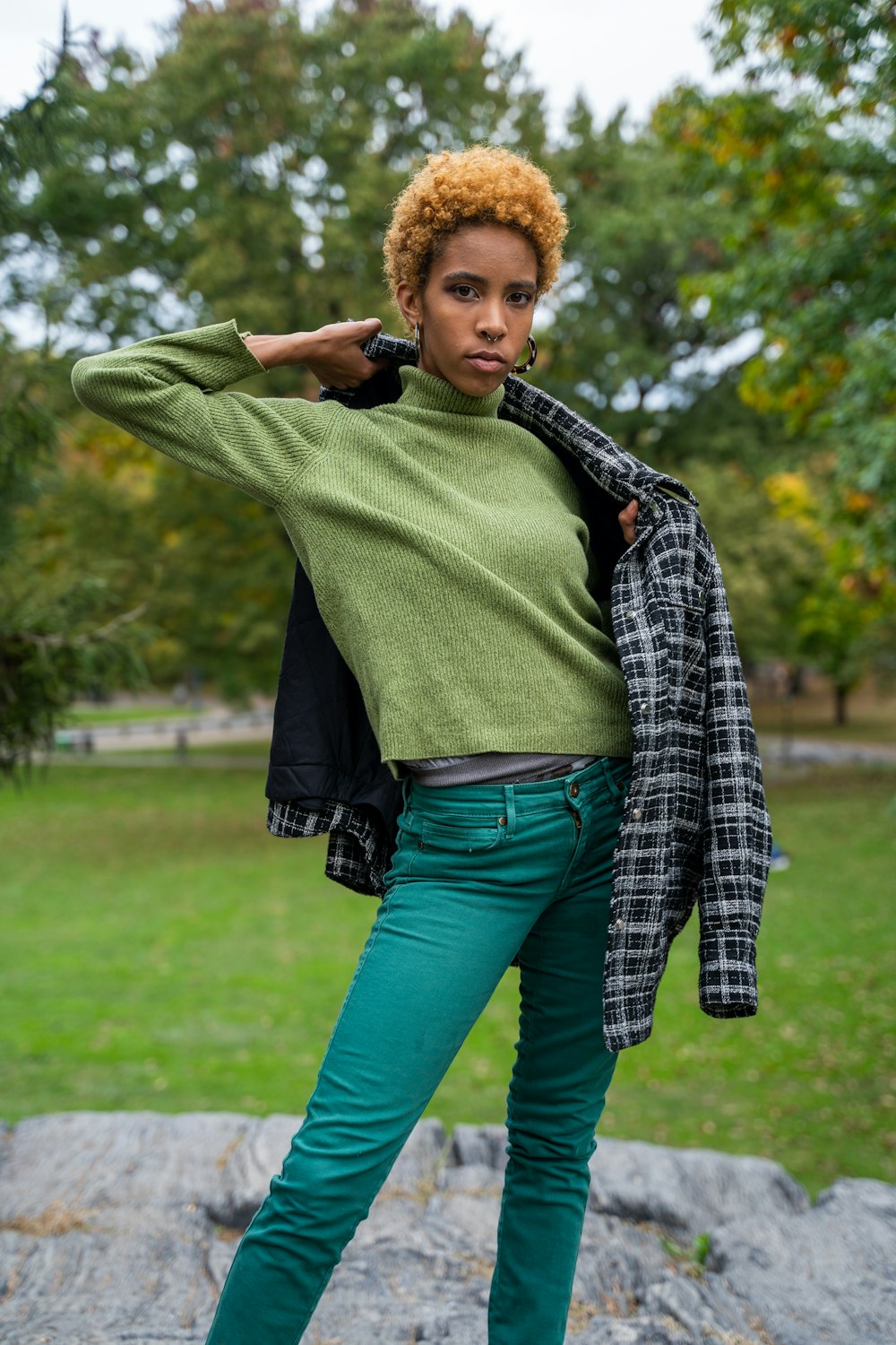 woman in green long sleeve shirt and blue denim jeans standing on green grass field during