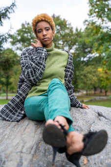 boy in green and white plaid dress shirt and green pants sitting on concrete floor during