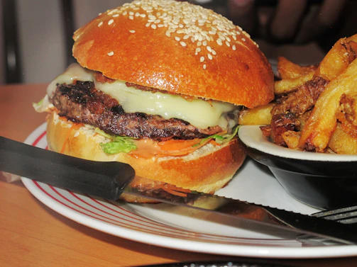 A juicy, stacked burger dripping with melted cheese and fresh toppings on a soft bun, served with crispy fries.