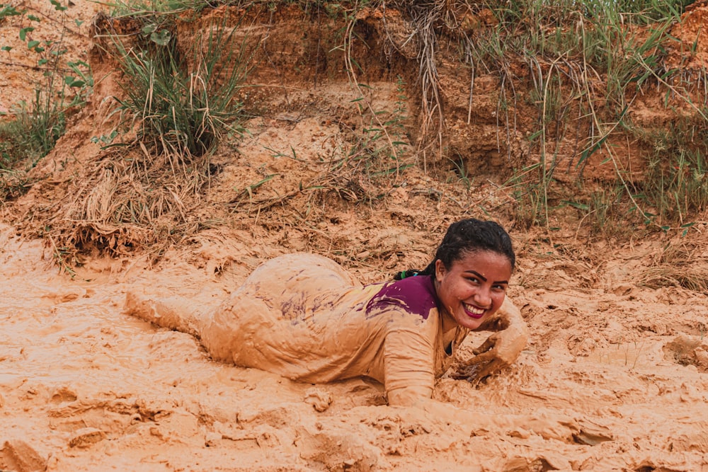 man in pink shirt lying on brown sand during daytime