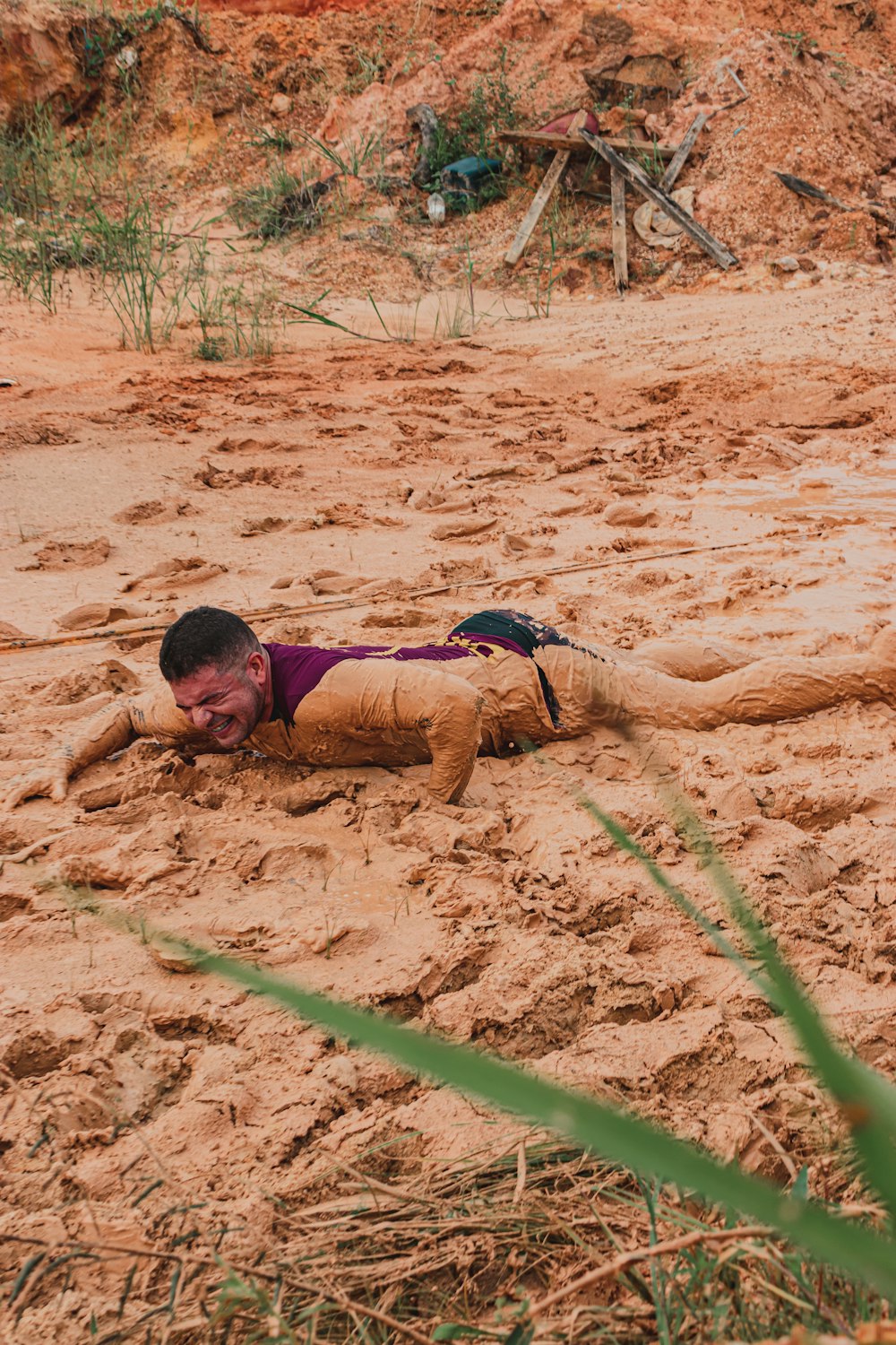 menino na camisa vermelha e azul deitado na areia marrom durante o dia