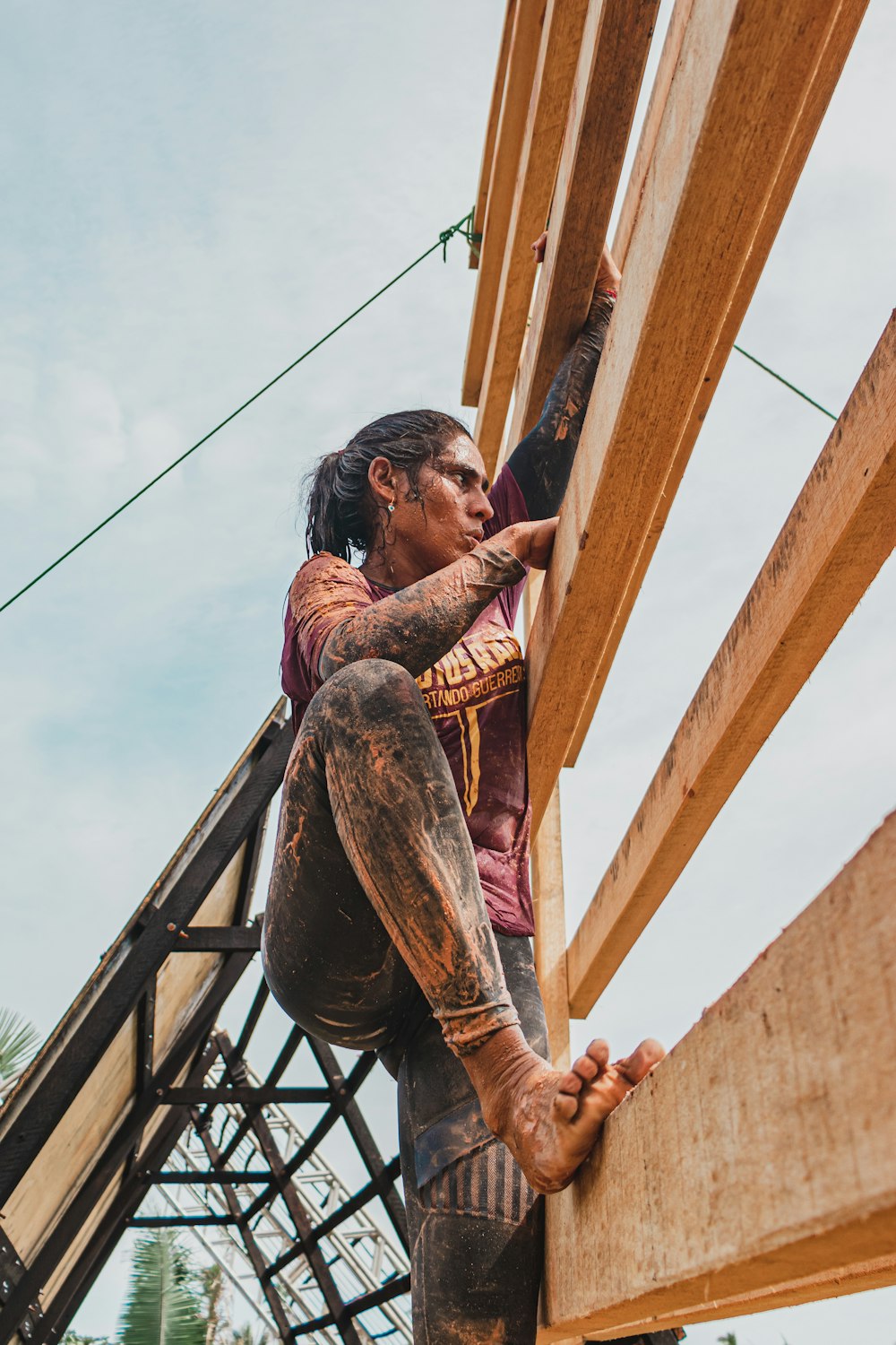 man in brown and black plaid shirt climbing on brown wooden ladder during daytime