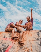 Men pushing through a tough obstacle course together under a bright sky.