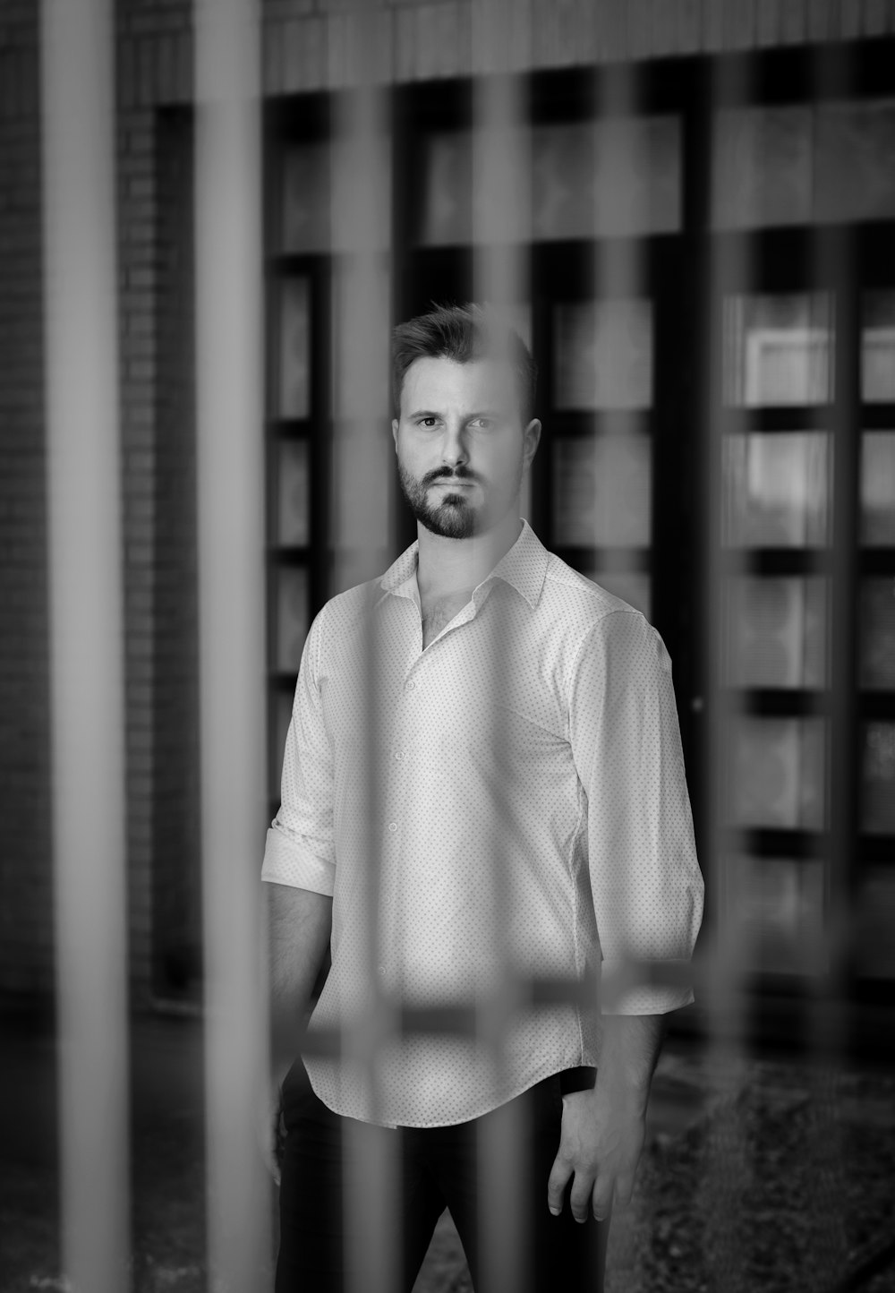 man in white button up shirt standing in grayscale photography
