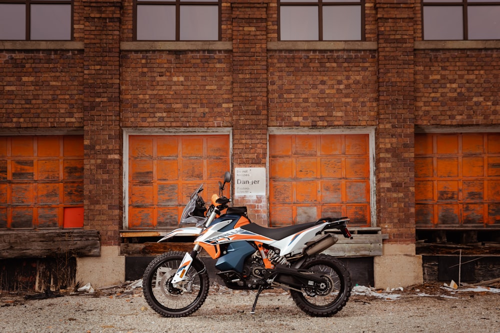 black and blue naked motorcycle parked beside brown brick wall