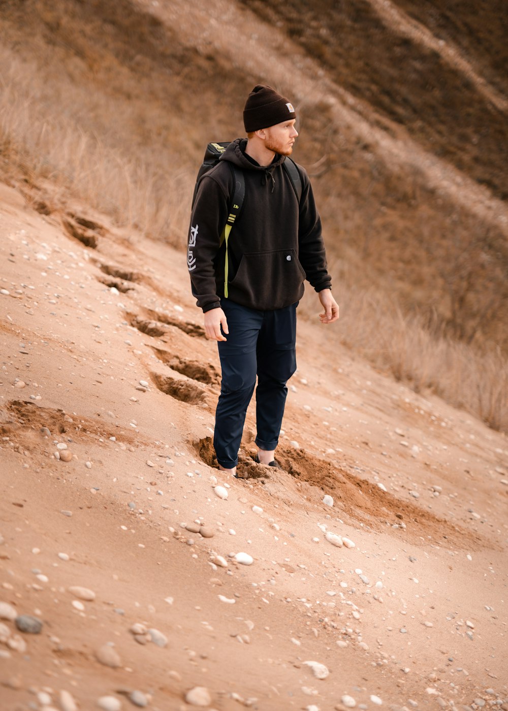 man in black jacket walking on dirt road during daytime