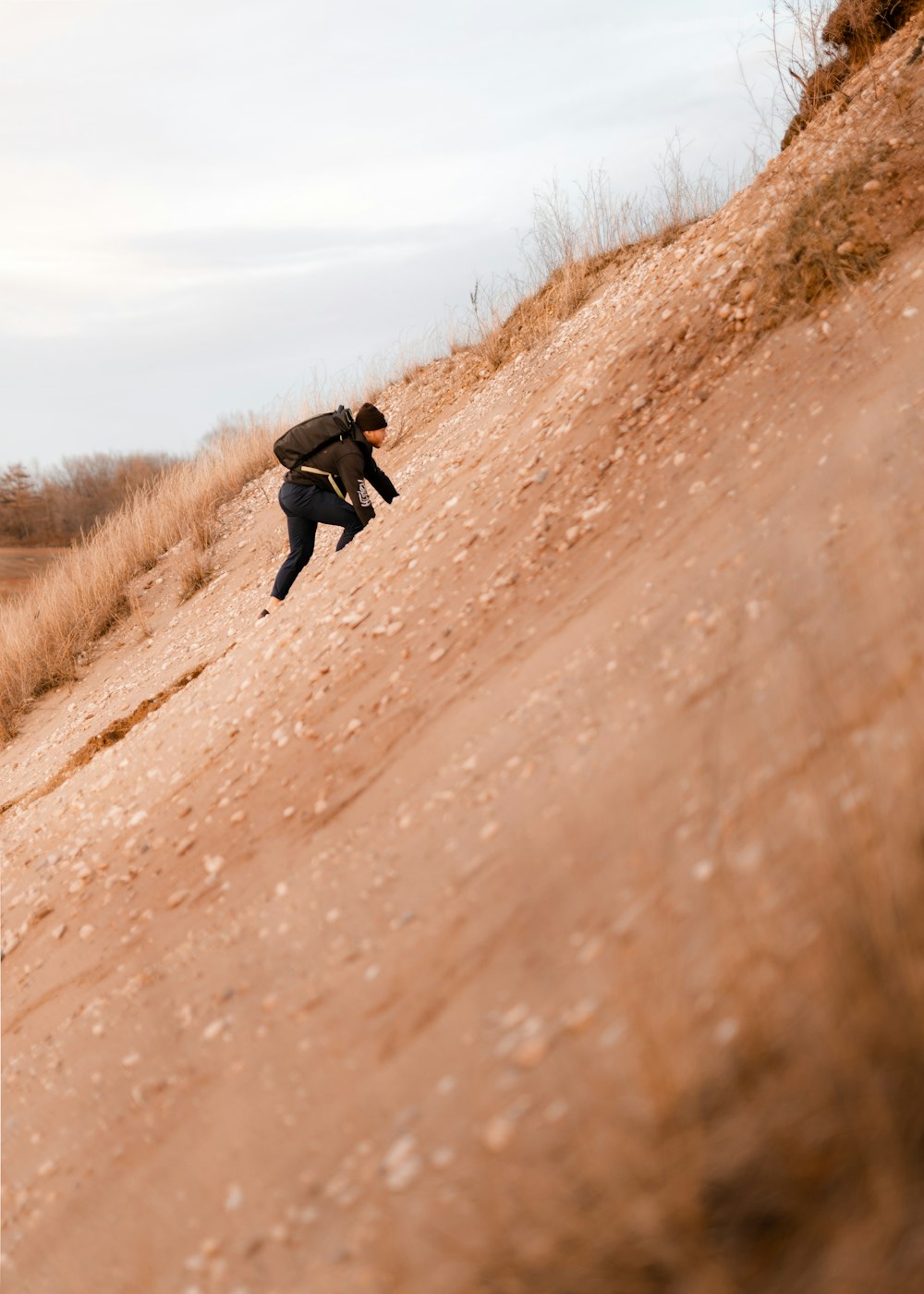 woman in black jacket and black pants running on brown dirt road during daytime