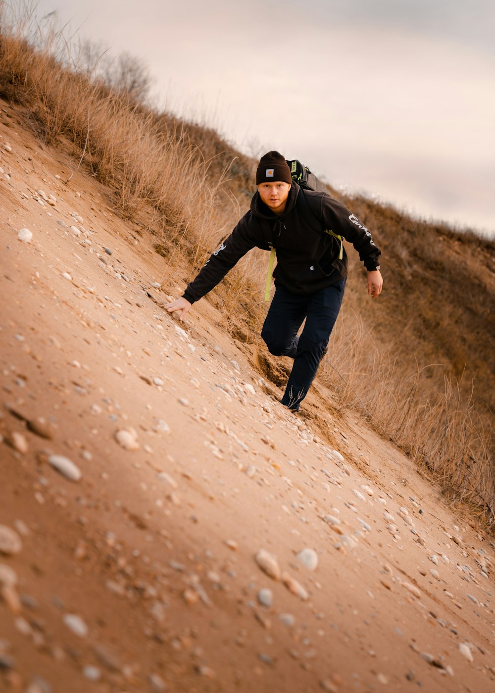 man in black jacket and black pants running on brown dirt road during daytime