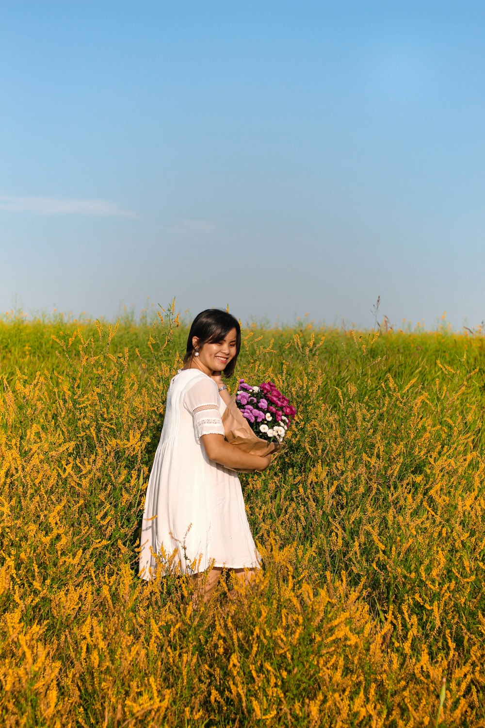 woman in white dress holding bouquet of flowers