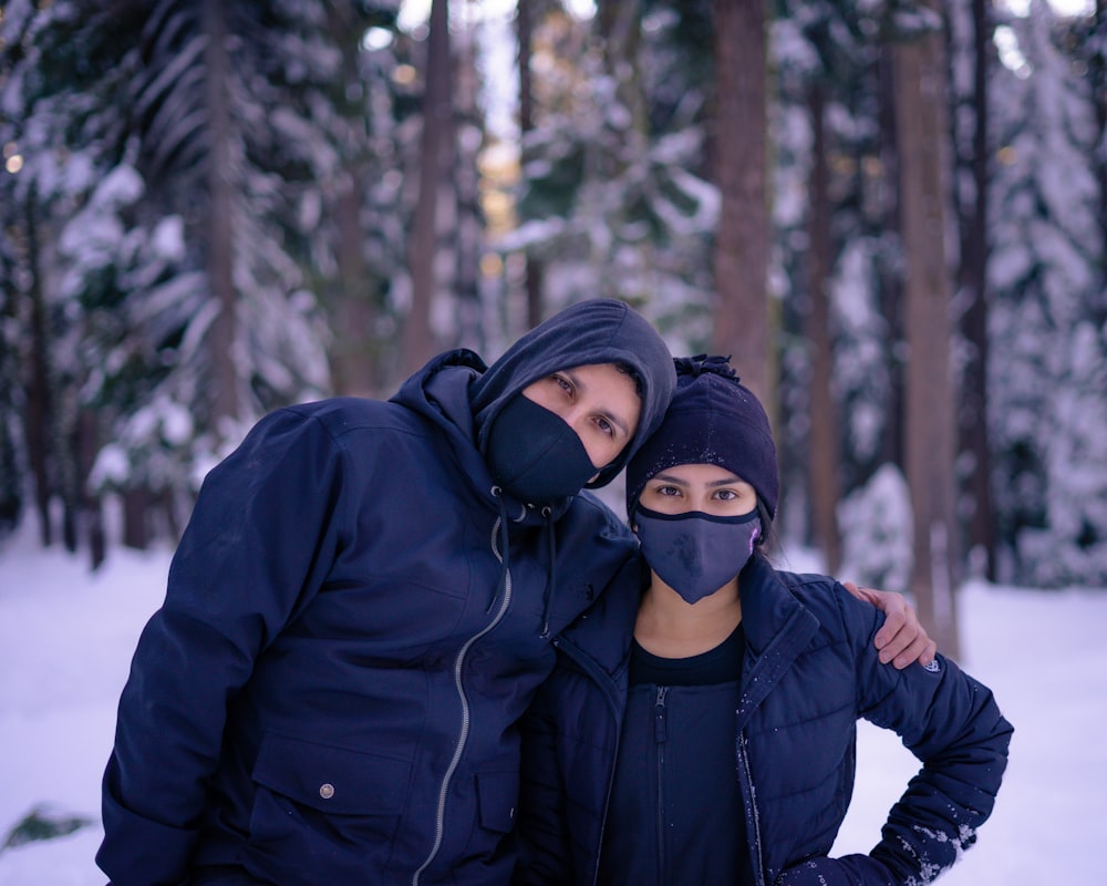 man in black jacket wearing black knit cap covering his face with his hand