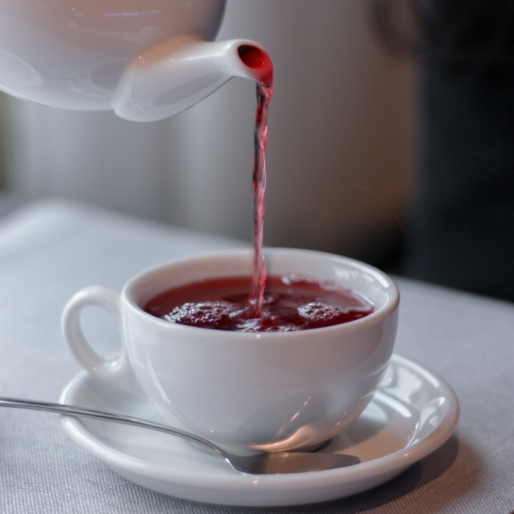 xícara de chá de cerâmica branca com líquido vermelho