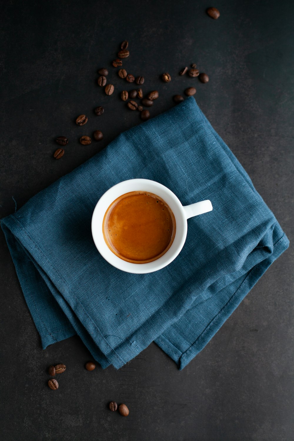 weiße Keramiktasse auf blauem Textil