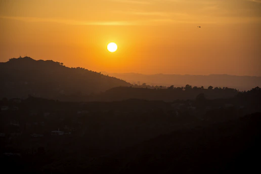 A vintage helicopter soaring over lush Vietnamese hills, bathed in golden sunset light.