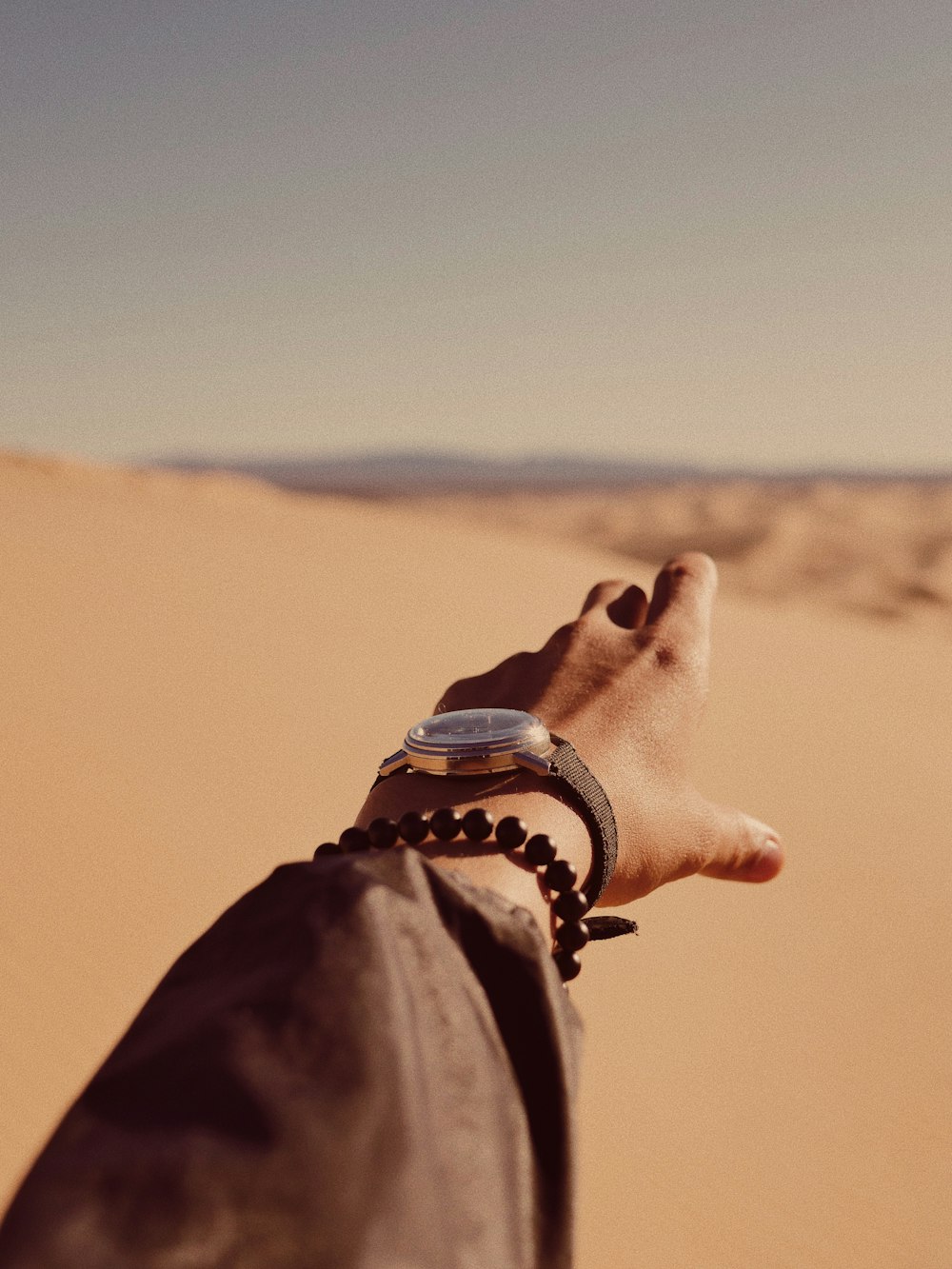 person in black leather strap watch and brown coat