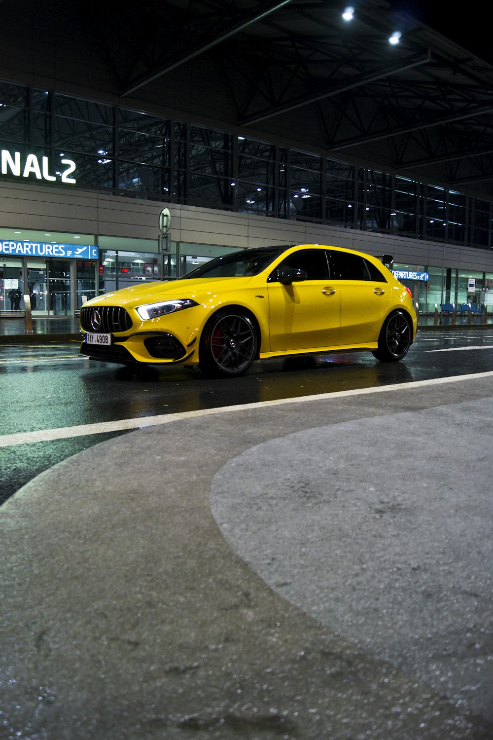 yellow coupe parked on gray concrete pavement