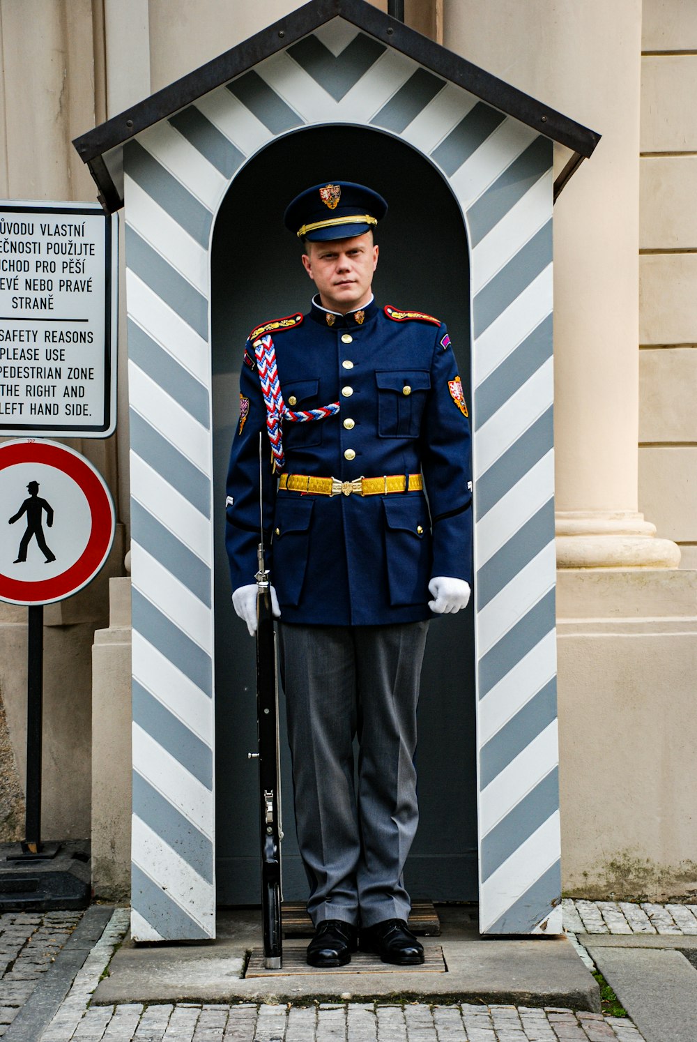 흰 벽 옆에 서 있는 파란색과 갈색 경찰 제복을 입은 남자