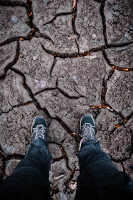 Close-up of sturdy hiking boots dusted with volcanic ash resting on a lava field.
