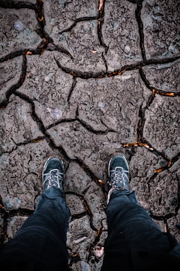Military boots firmly planted on rugged terrain with dust rising.