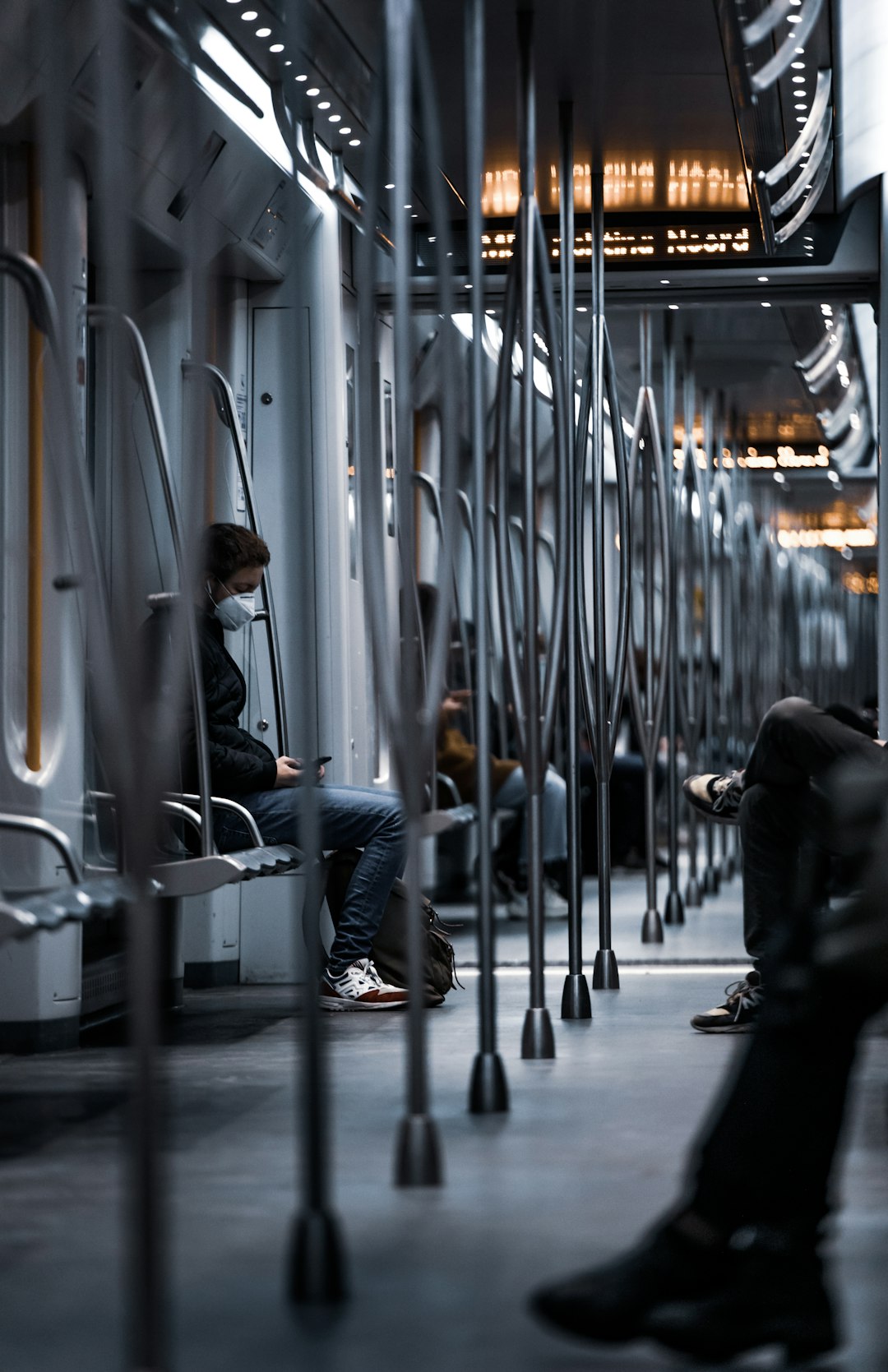 man in black jacket and blue denim jeans sitting on train seat