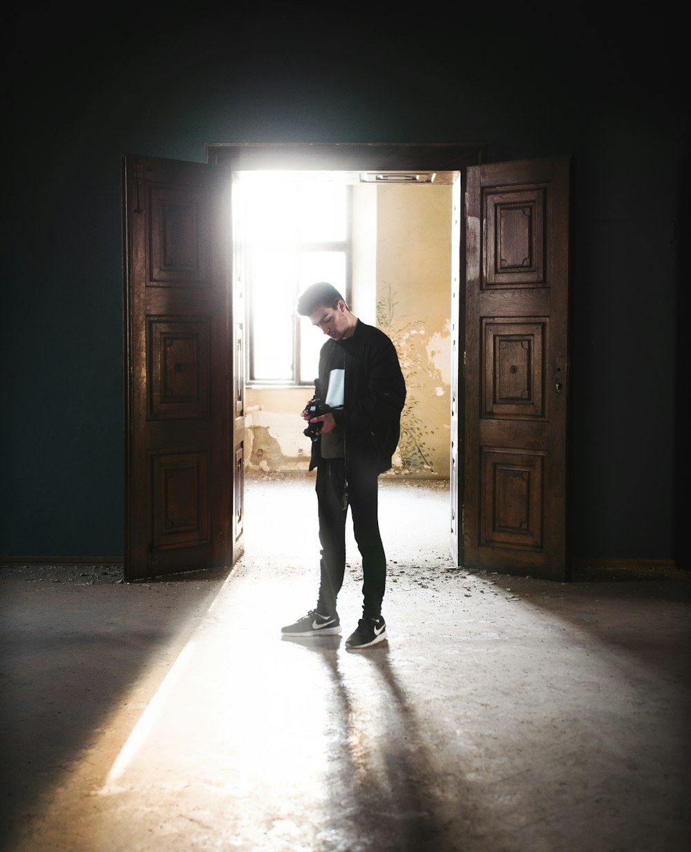 man in black jacket standing near brown wooden door